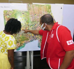 A Red Cross staff member looks at map of Old Harbour Bay with a Resilient Islands stakeholder. The map shows hazards, vulnerabilities and exposed areas in the community.
